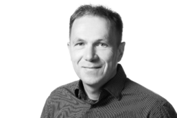 Billede af en smilende middelaldrende mand i stribet skjorte.